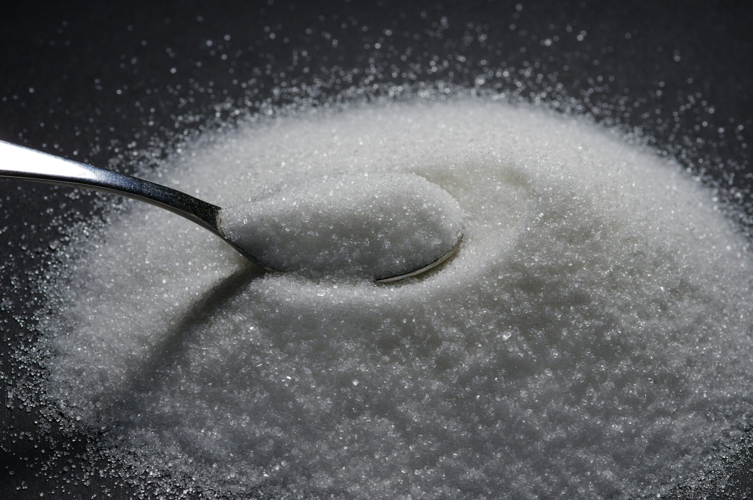 a tablespoon rests on a mountain of sugar